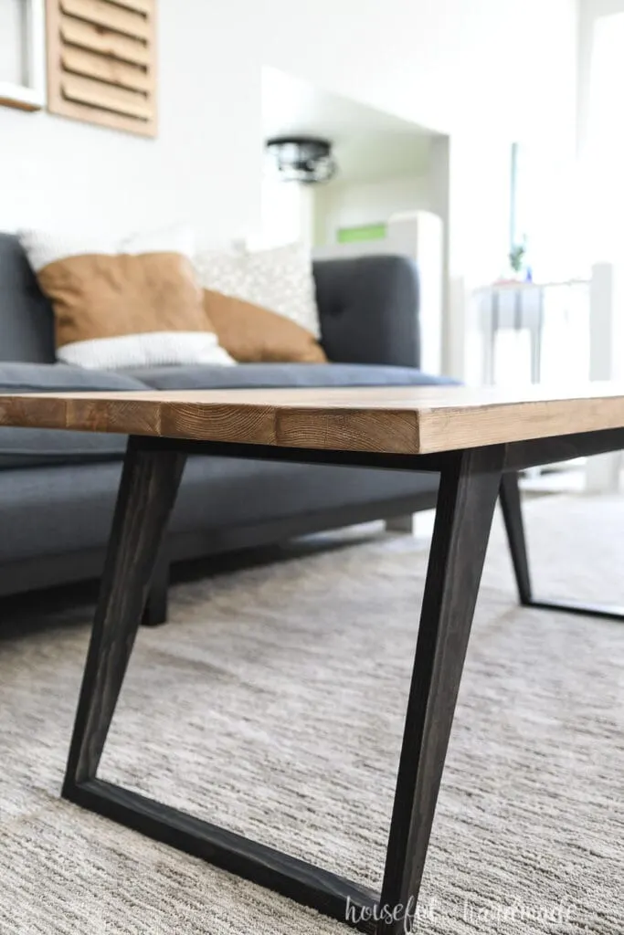 Side view of the modern coffee table with black stained angled legs. 