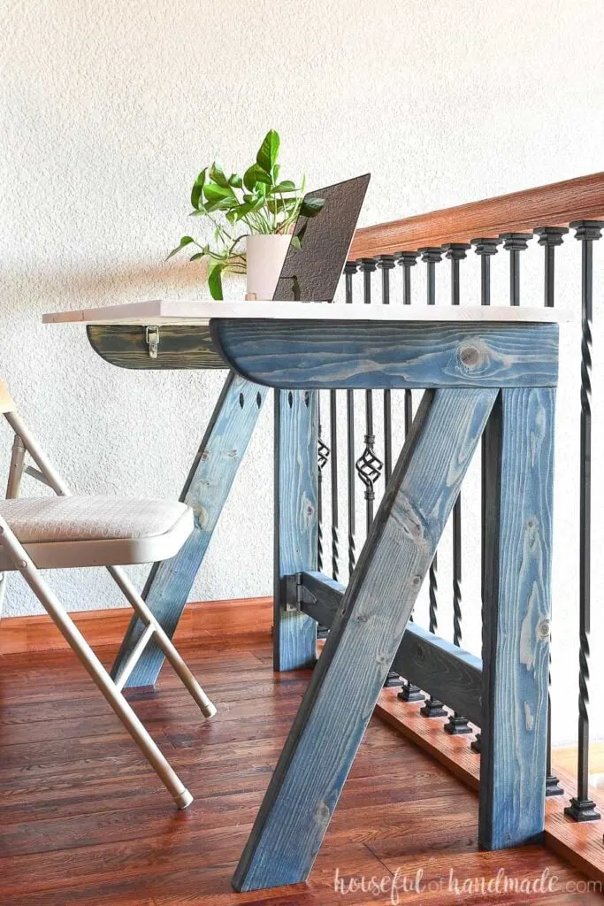 Blue and white DIY folding desk with a laptop and plant on top of it. 