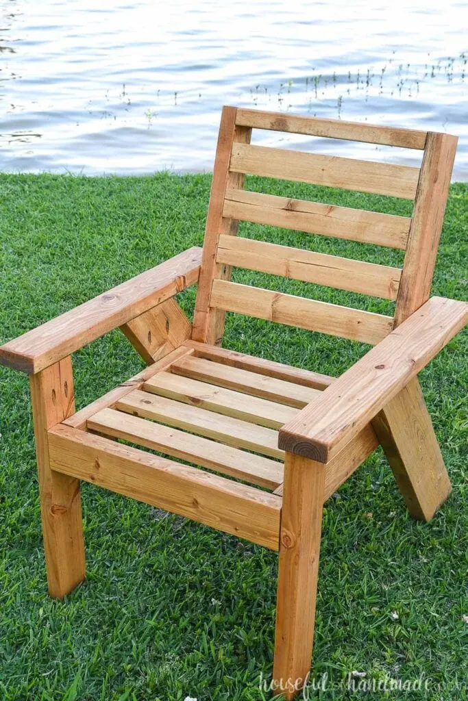Outdoor chair on the grass with no cushions on it. 