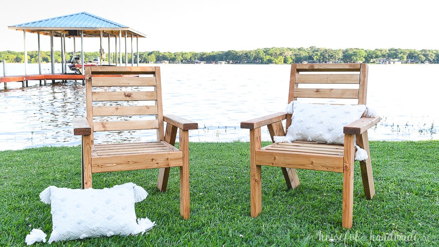 Two DIY outdoor chairs with pillows in front of a lake. 