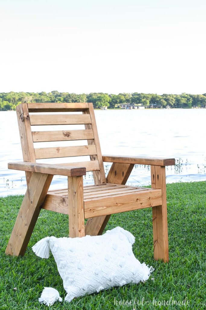 Outdoor lounge chair sitting on the grass in front of the lake.