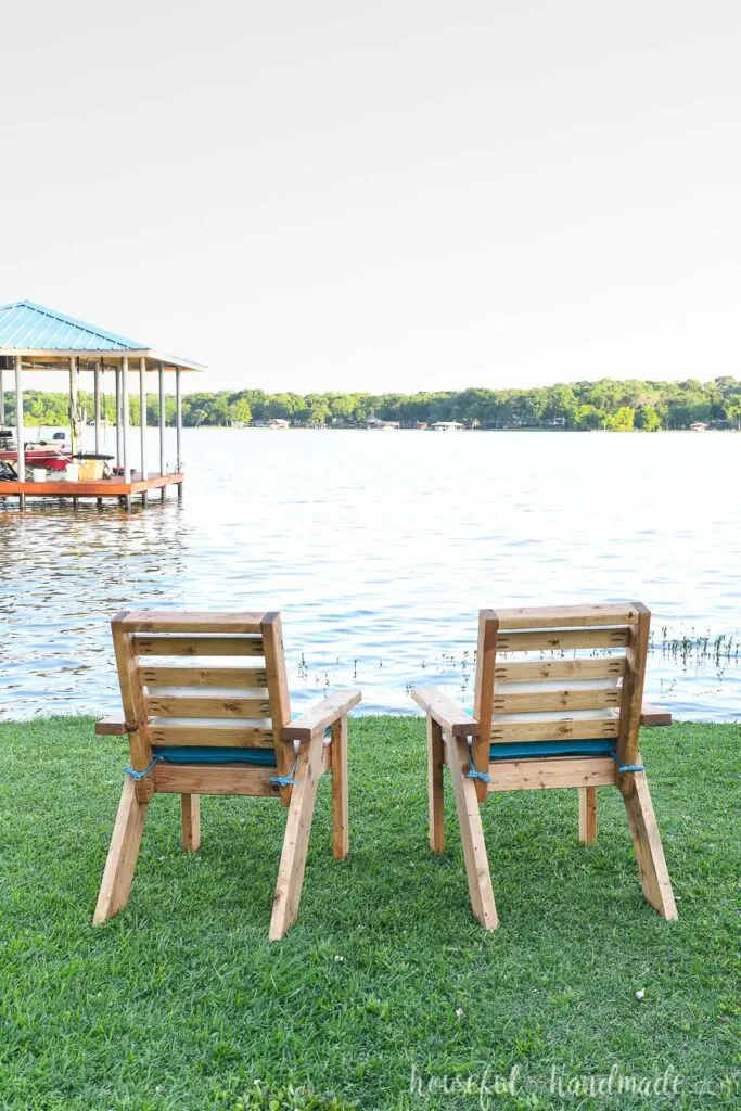The back of the two outdoor chairs as they are looking over the lake. 