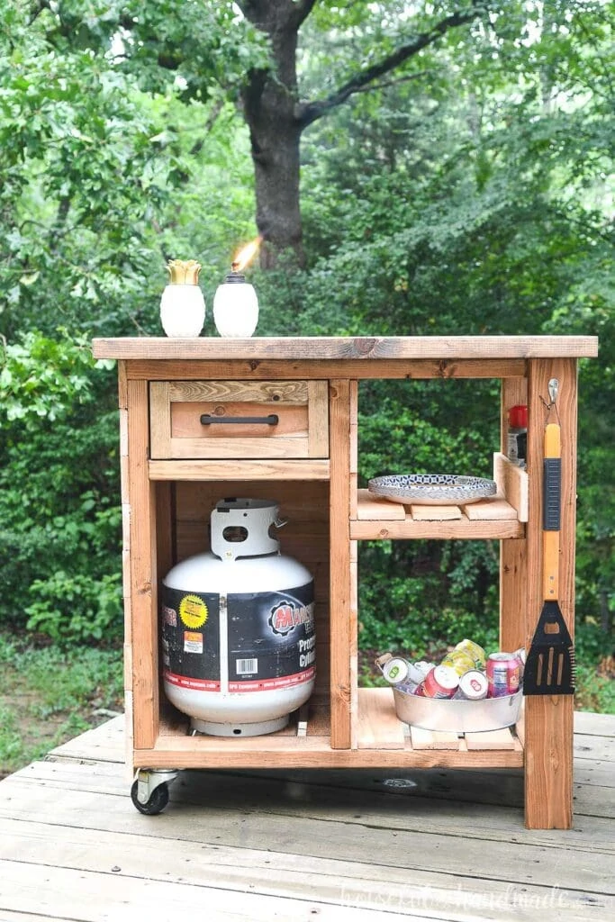 DIY grill cart made from 2x4s and cedar fence pickets  with storage and hooks for hanging grill tools. 