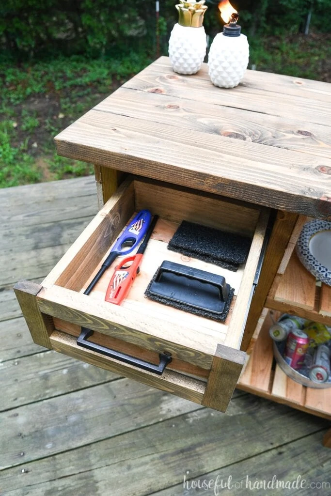 Close-up of the drawer on the grill table open with grill accessories inside. 