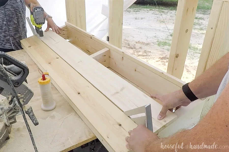 Attaching the 1x6 slats for the back rest with nails and spacing them with speed squares. 