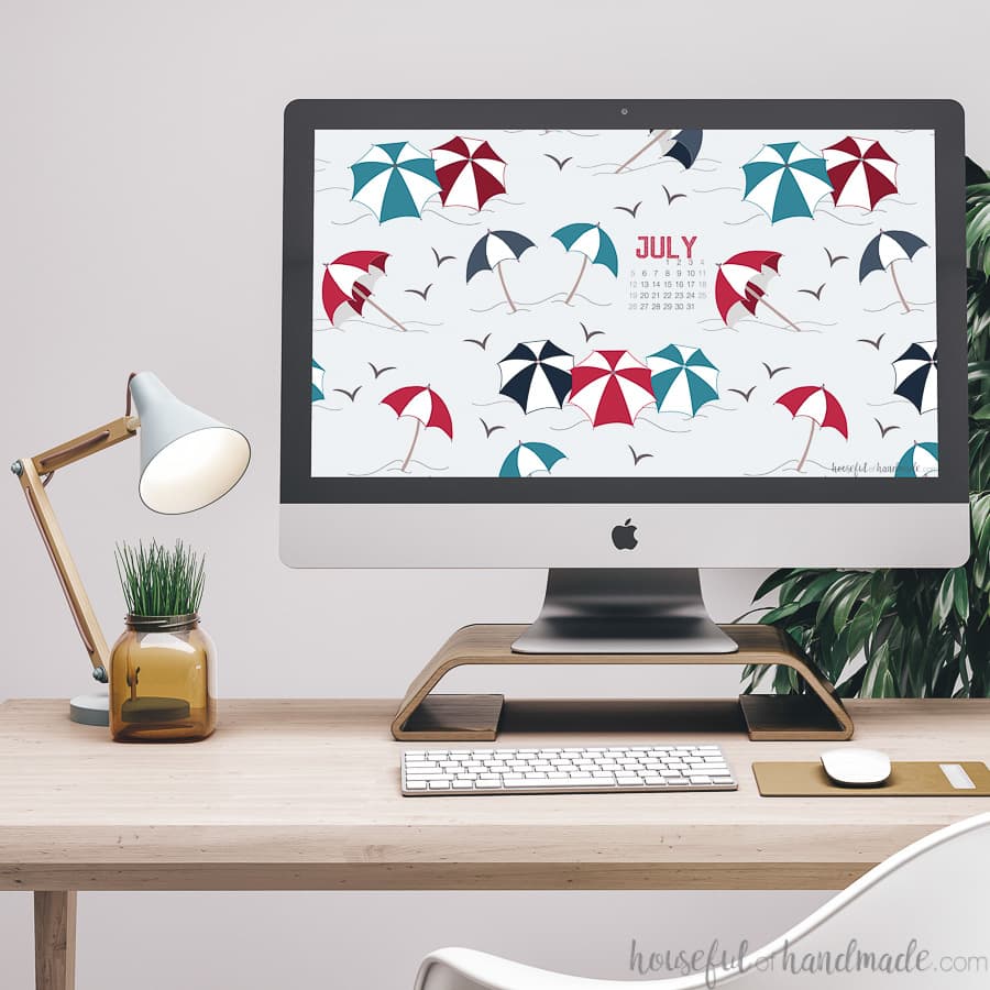 Desk with computer and summer umbrella digital background on the screen.