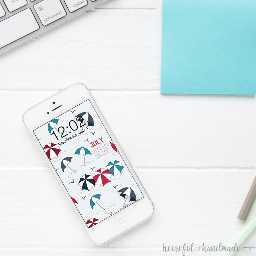 Smartphone on a desk with the red, navy and turquoise beach umbrella background as the home screen wallpaper.