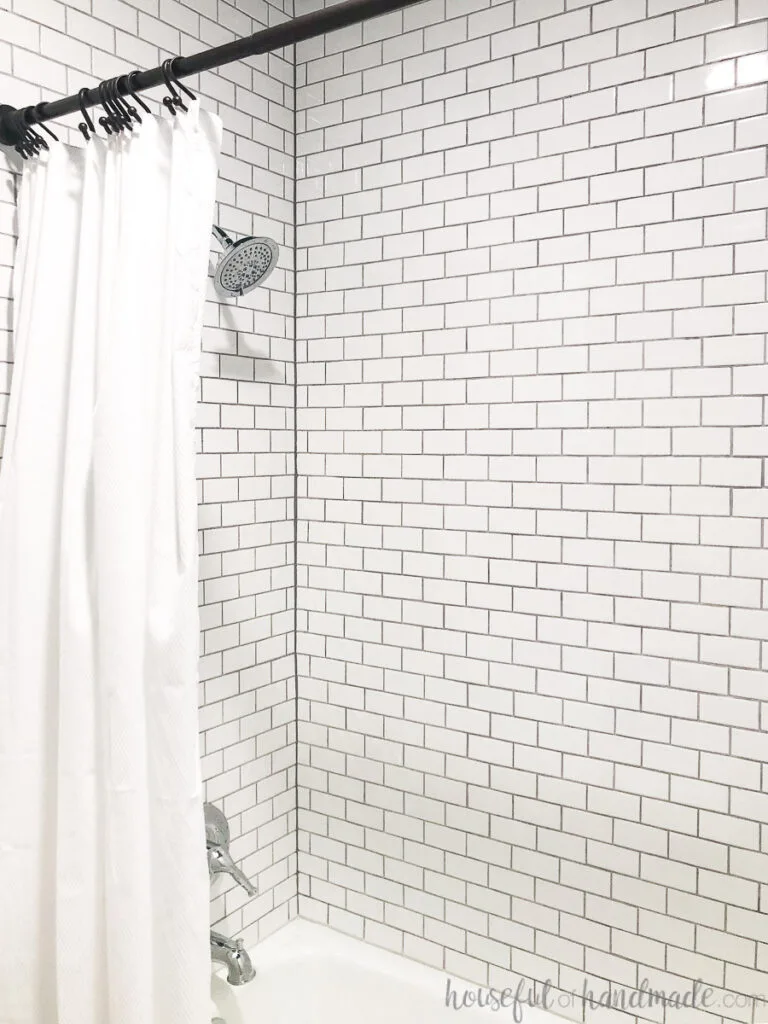 Bathtub and surround tiled with small subway tiles in white. 