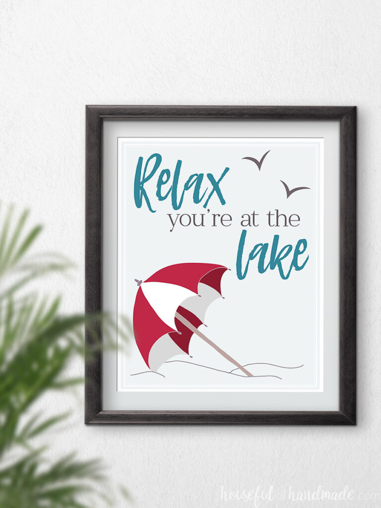 Red beach umbrella art with text "relax your at the lake" in a frame.