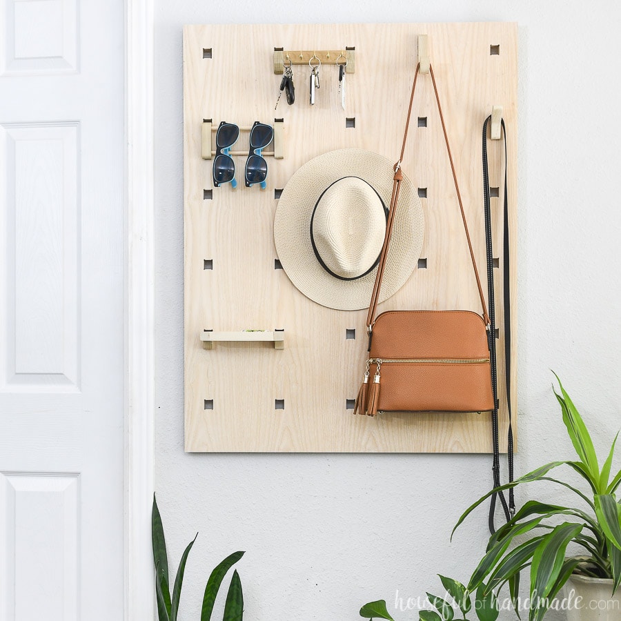 Entryway organizer made from plywood hanging on the wall next to a door.