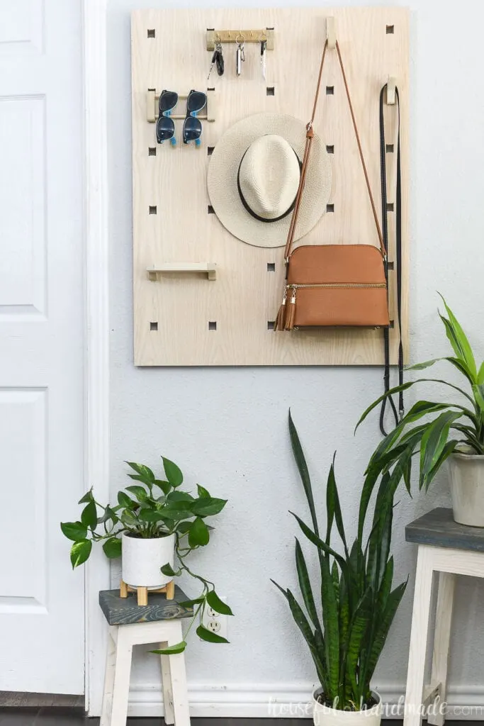 Straight on picture of the modular entryway organizer with a purse, hat, sunglasses and keys hanging on it. 
