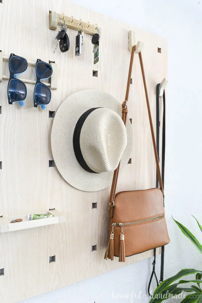 Close up view of the entryway wall organizer with purse, hat and more hanging on it.