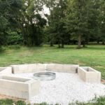 DIY fire pit area with stacked cinder blocks surrounding a metal fire ring and limestone pebbles between them.
