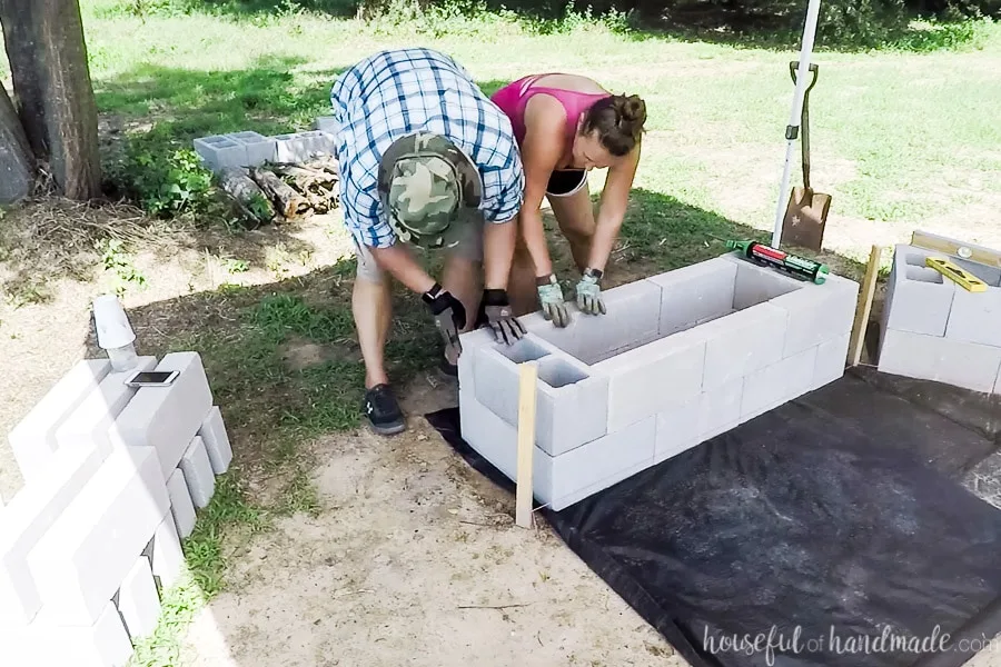 Finishing assembling the bases of concrete blocks for the DIY fire pit area. 