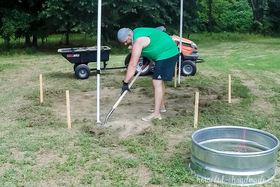 Using a shovel to remove the grass and top layer of soil from where the new fire pit will be. 