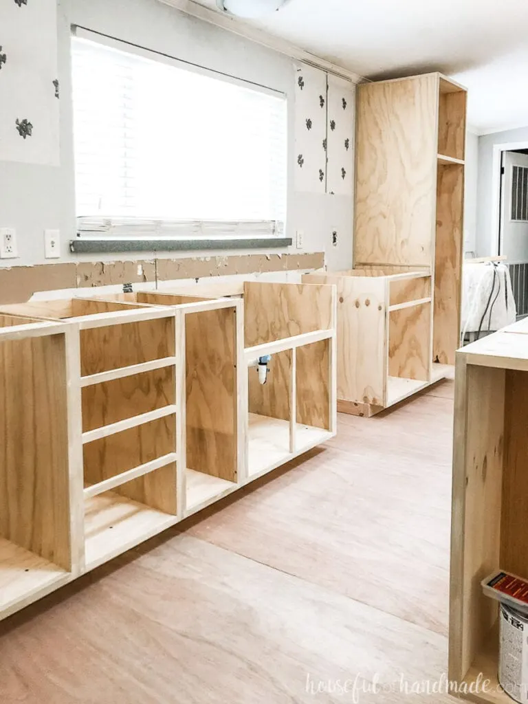 View of the DIY kitchen base cabinets installed under the window with a farmhouse sink base. 