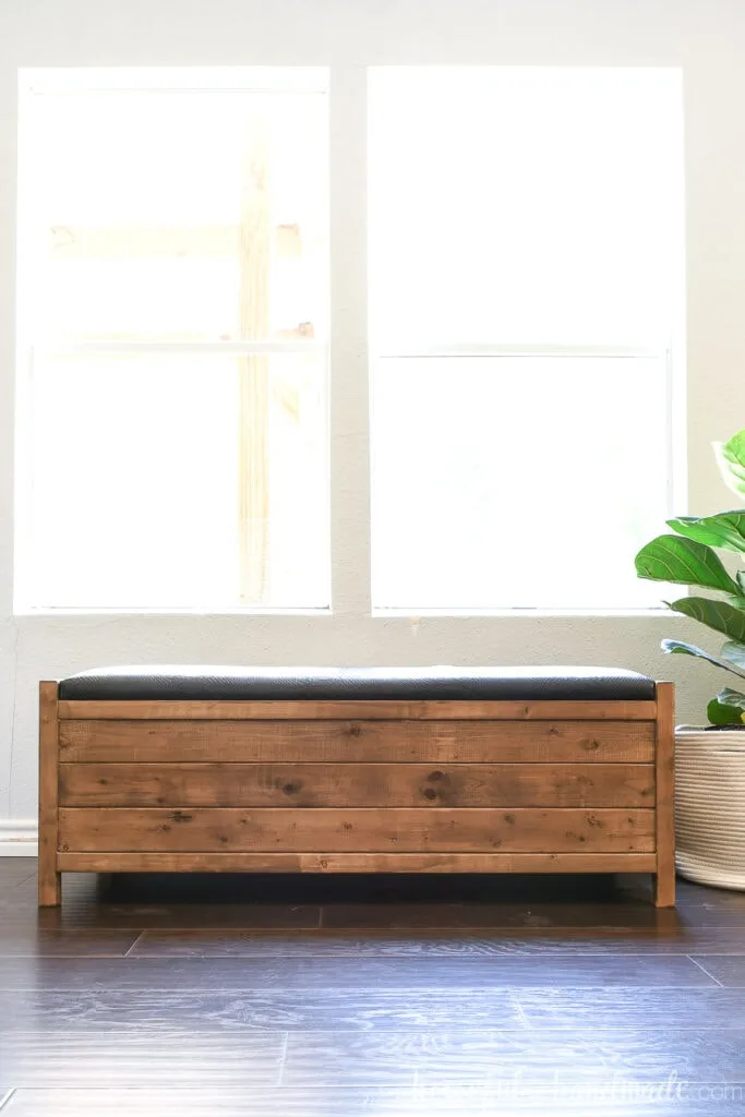 Front view of the simple wood storage bench with black leather top that lifts up.