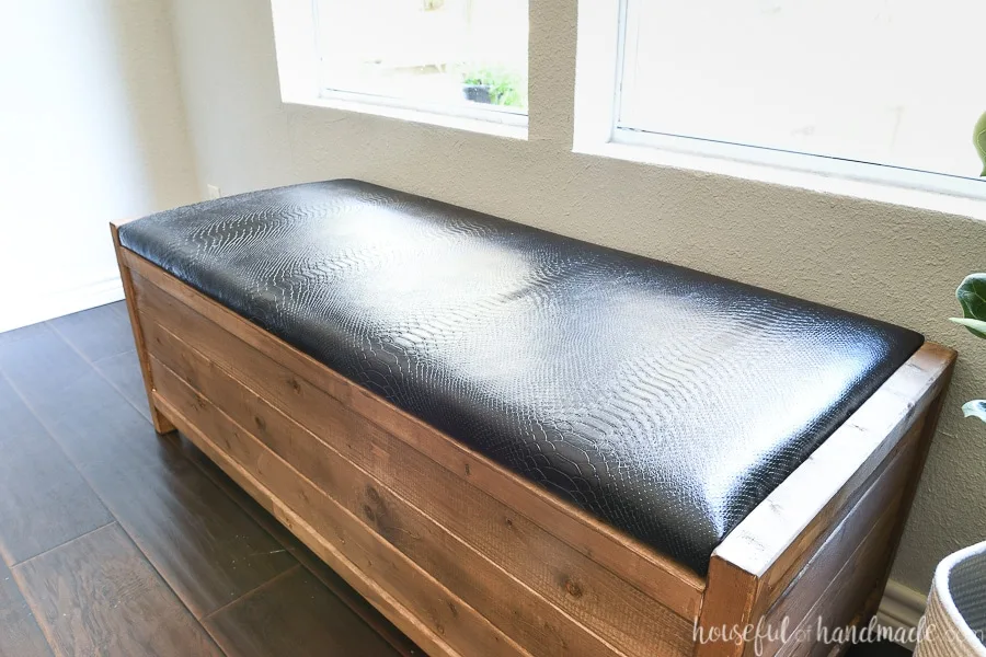 Close up of the black leather upholstered top of the wood bench. 