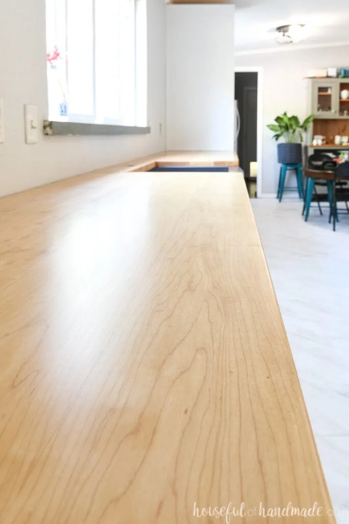 Close up view of the light hardwood kitchen countertops with a farmhouse sink installed.