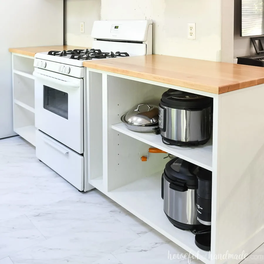 White cabinets around the stove with solid wood countertops sealed with a matte finish on them. 