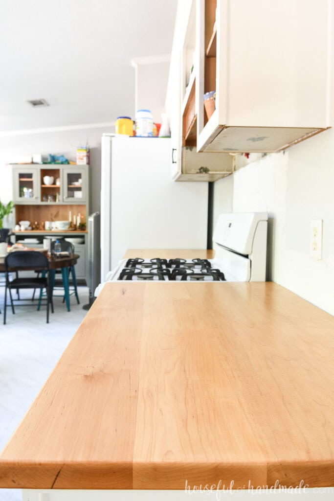 Looking down the side of the kitchen with the range and fridge and DIY wood countertops on the cabinets between them. 