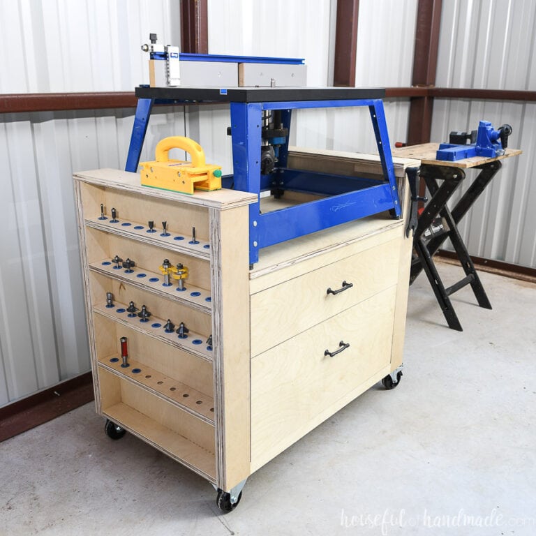 Angled shot of the DIY bench top router table made from plywood with a blue framed bench top router on it showing the side with the router bits storage.