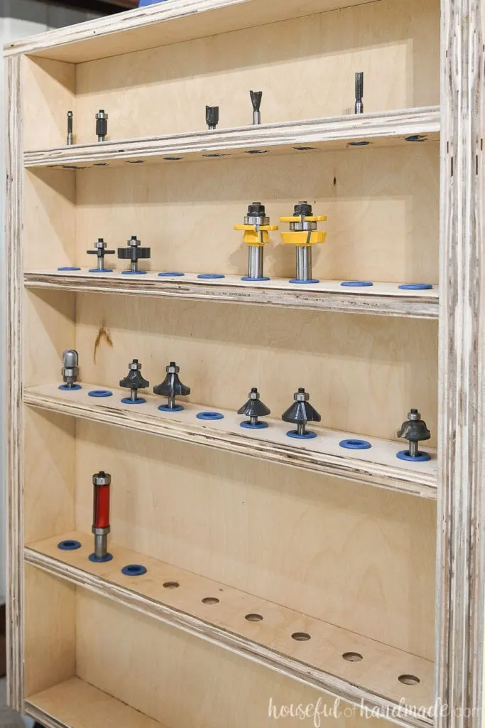 Close up shot of the router bit storage shelves on the side of the DIY router table with router bits installed in Rockler router bit inserts. 