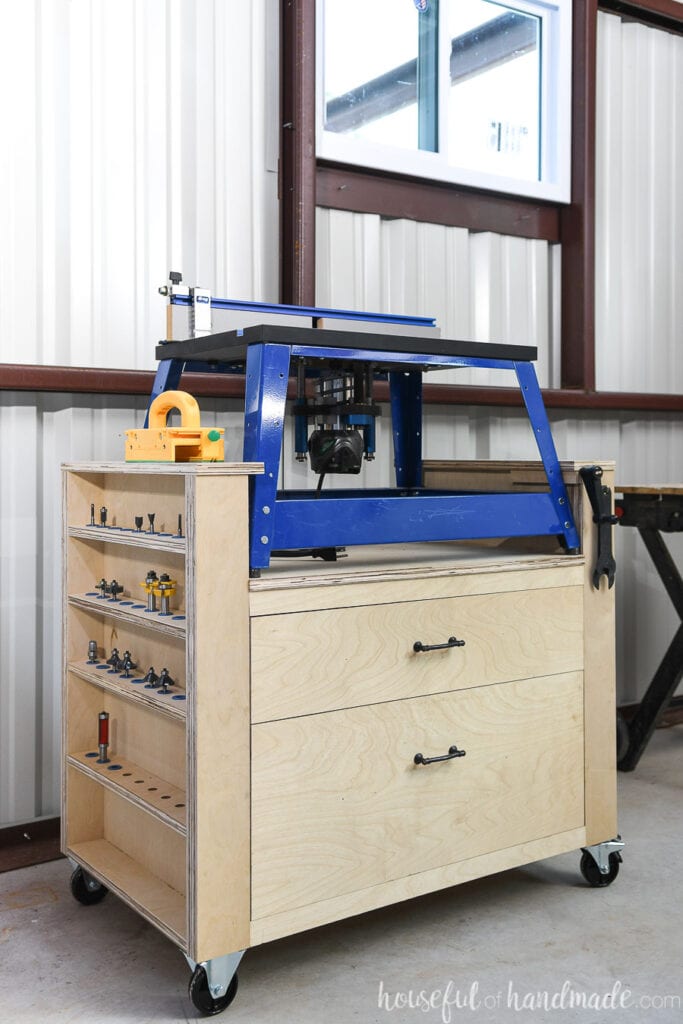 Bench top router table stand build from plywood with router bit storage on one side and 2 large drawers in the center. 