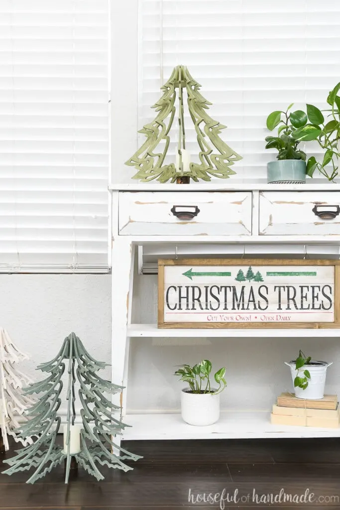 Christmas vignette on a white console table with 3D wood Christmas trees and a Christmas tree farm sign.