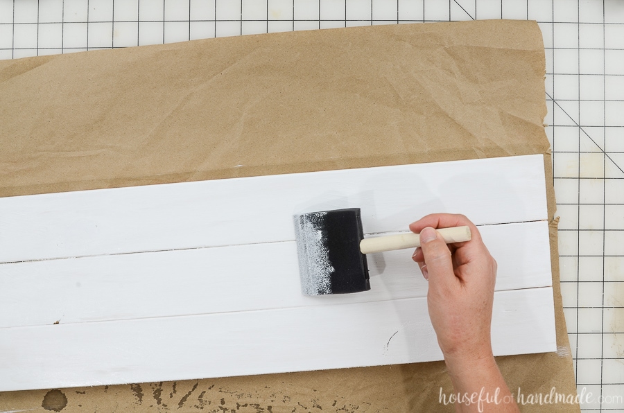 Painting one side of the wood sign white with a foam brush.