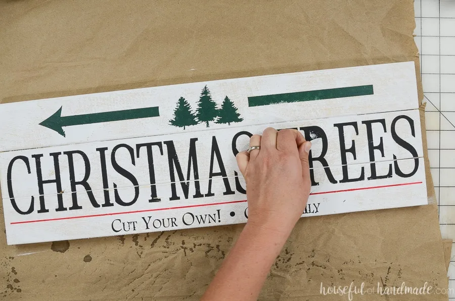 Peeling off the last of the vinyl stencil revealing the Christmas tree farm sign.