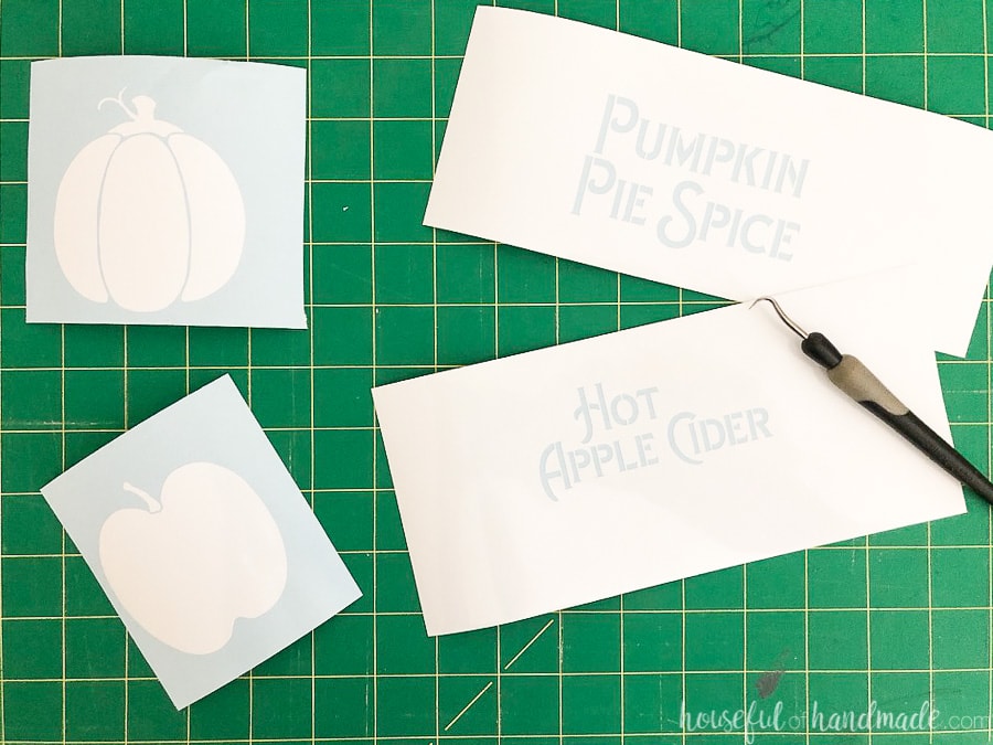 Four vinyl stencils cut out of white vinyl for the kitchen canister craft.
