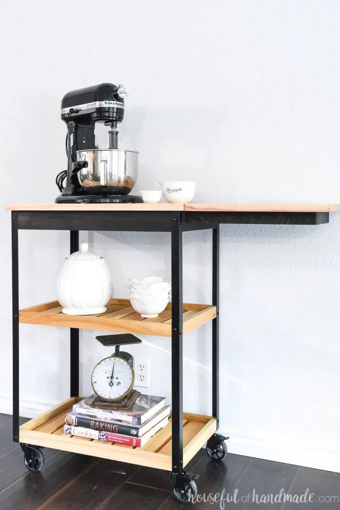 DIY kitchen cart on wheels with a drop-down leaf raised and two shelves for storage. 