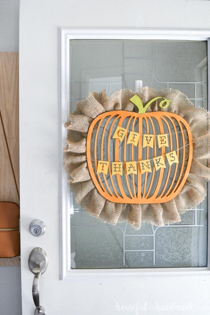 Close up of the wood pumpkin shaped wreath with burlap around the outside and the Give Thanks banner hanging on it. 