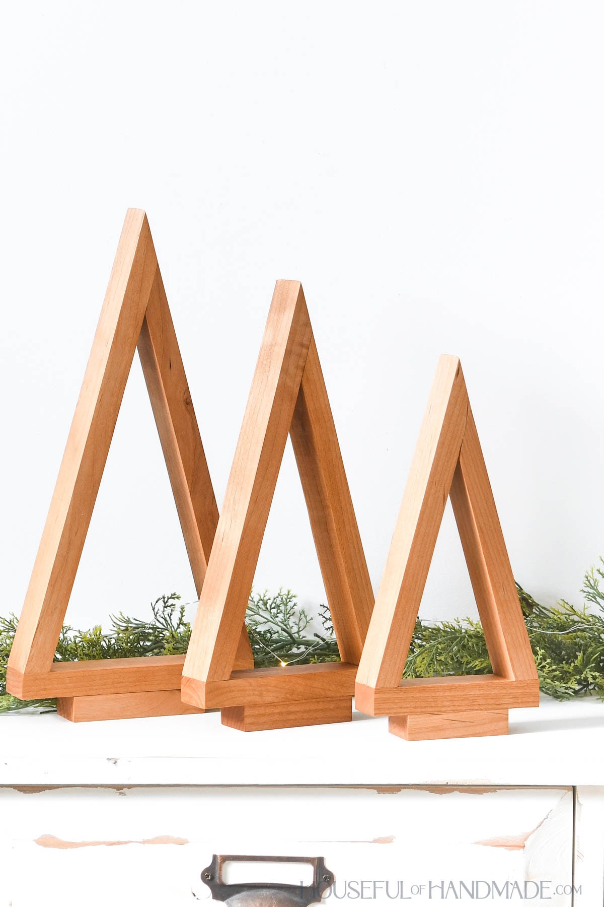 Three simple wood decorative Christmas trees in a line from small to large. 