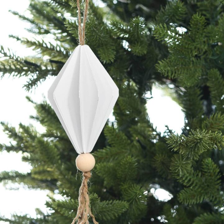 Diamond shaped paper Christmas ornament hanging on a Christmas tree.
