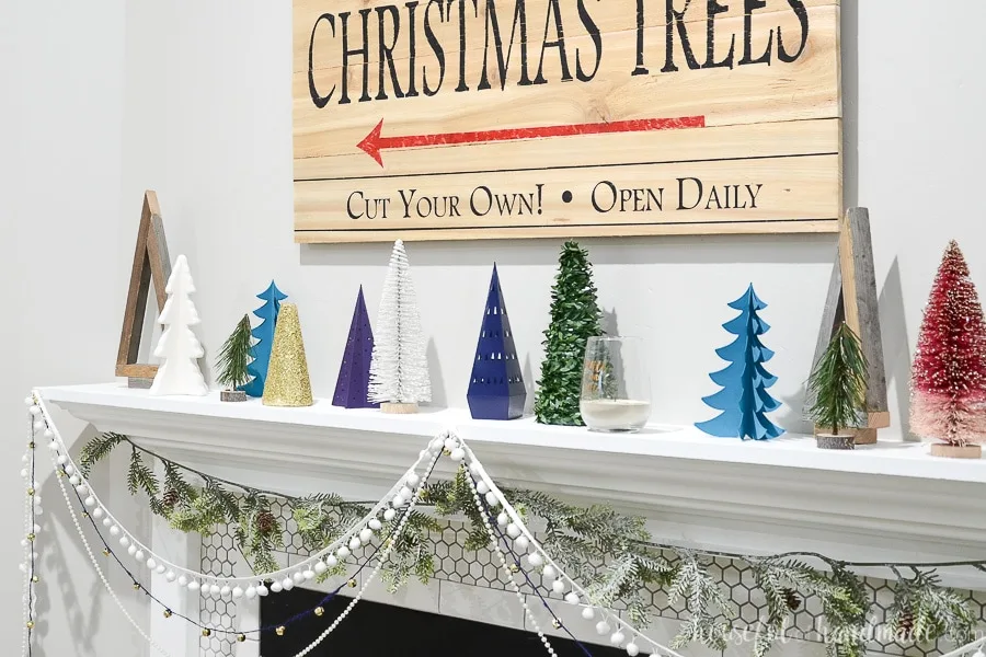 White mantel with lots of Christmas trees on it, including the wood Christmas trees made from 1x2 boards.