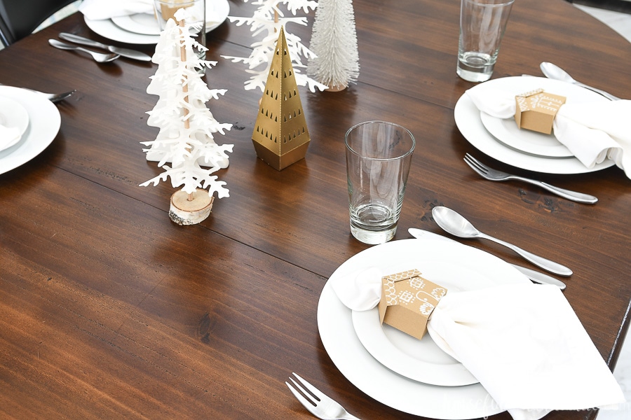 Looking on top of a table set for Christmas with Christmas trees and gingerbread house napkin rings.
