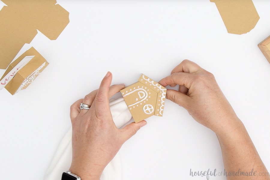 Threading a white cloth napkin through the center of the paper gingerbread house napkin ring.