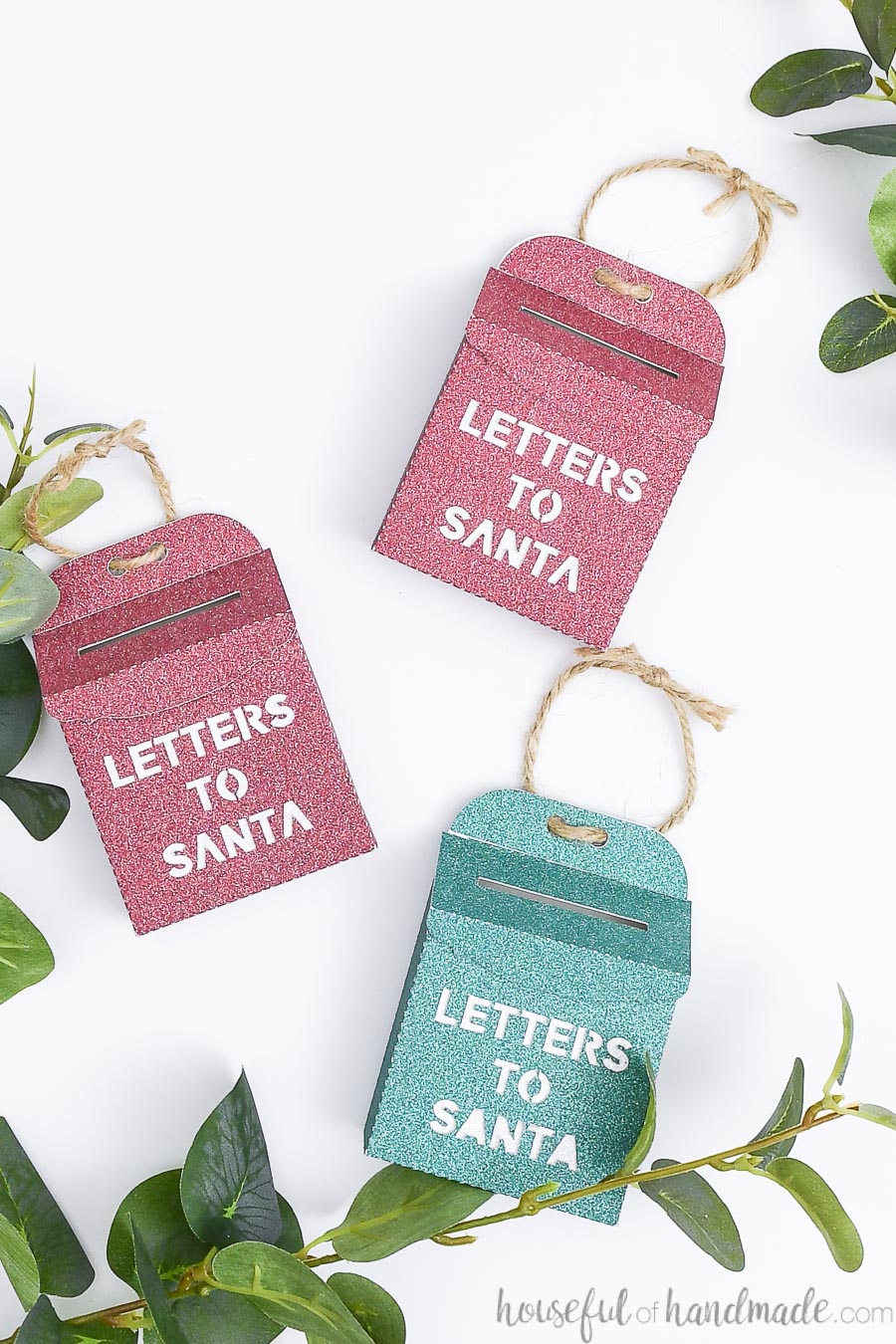 Three glittery Letters to Santa mailbox ornaments on a white background.