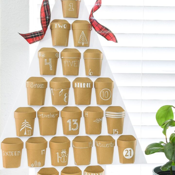 White Christmas tree shape with 24 paper pockets on the front decorated with a number for a Christmas countdown calendar.