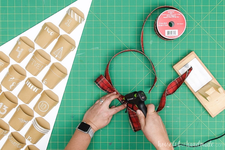 Glueing together a simple bow made from Christmas plaid ribbon.