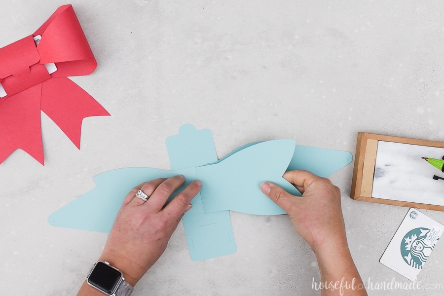 Glueing the bow tails to the back of the second paper bow made from blue cardstock.