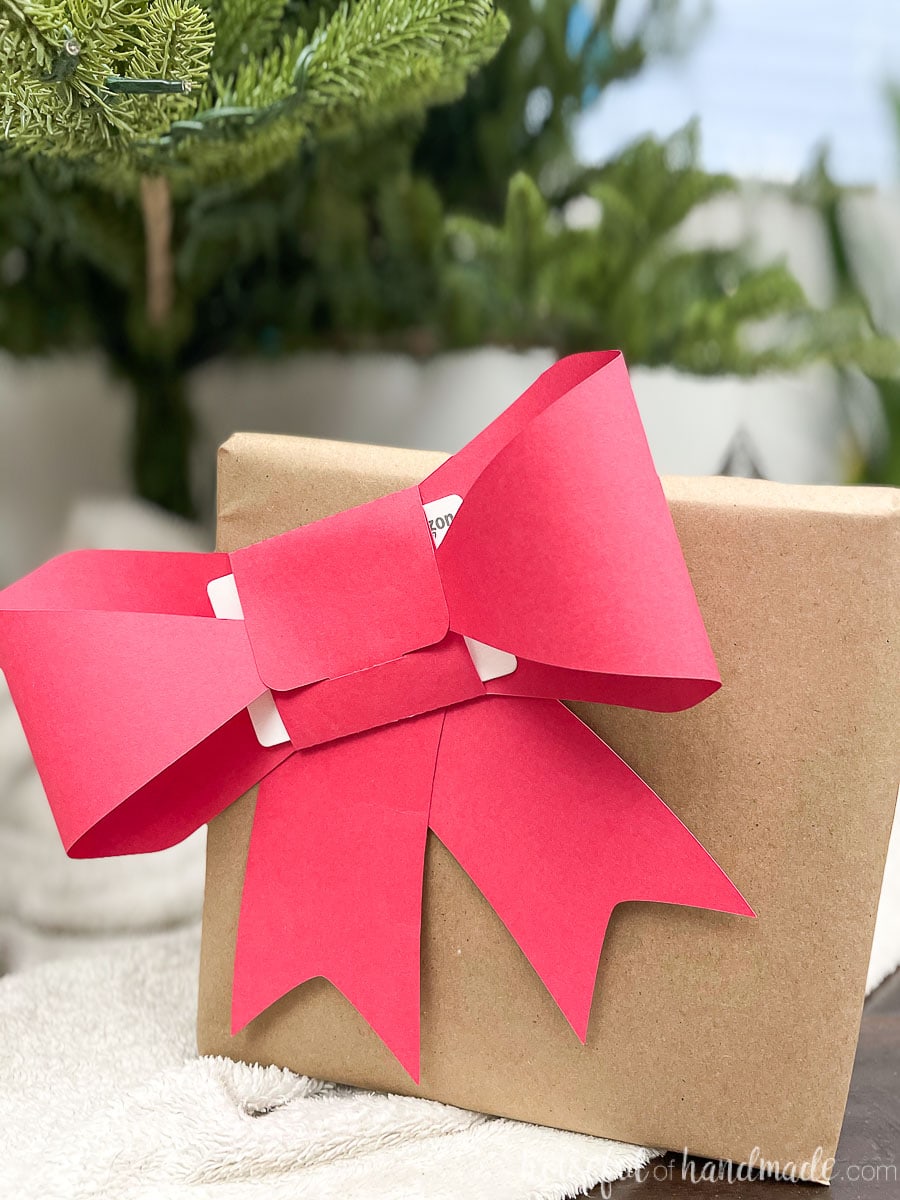 Christmas present wrapped in brown paper with a red paper bow gift card holder on the front.