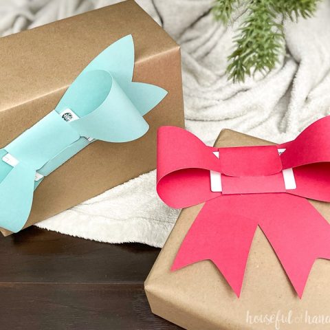 Two presents wrapped in brown paper with large paper bows folded around gift cards taped to the front.