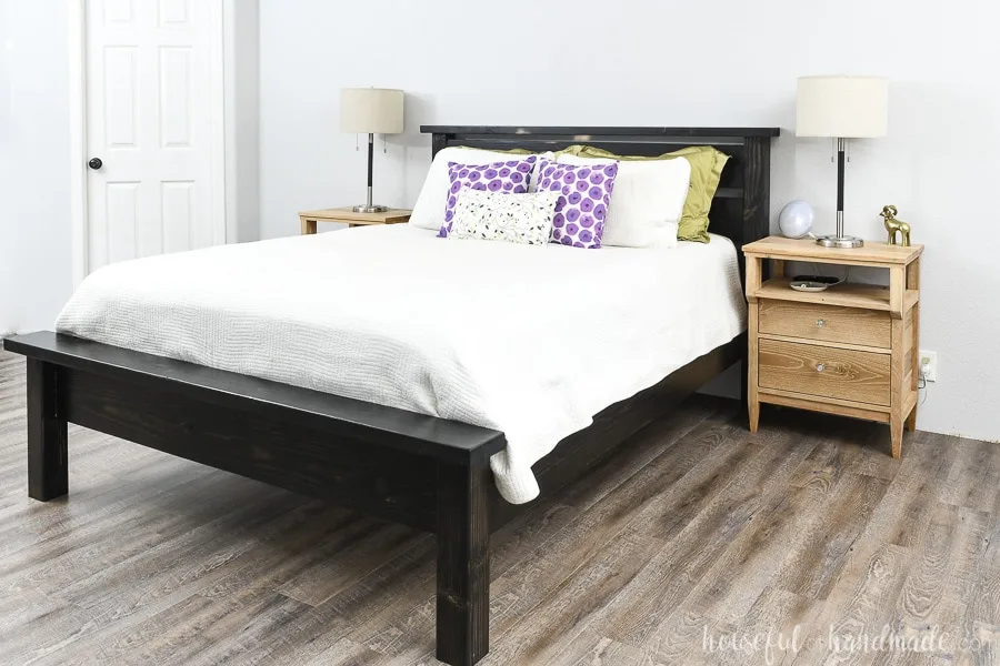 Easy to build DIY bed frame stained black with white bedspread and colorful pillows. 