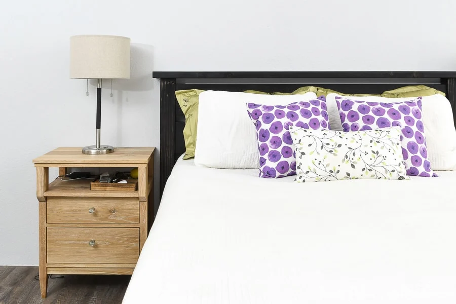 Straight on view of the DIY queen bed frame with a mattress inside and pillows leaning on the headboard. 