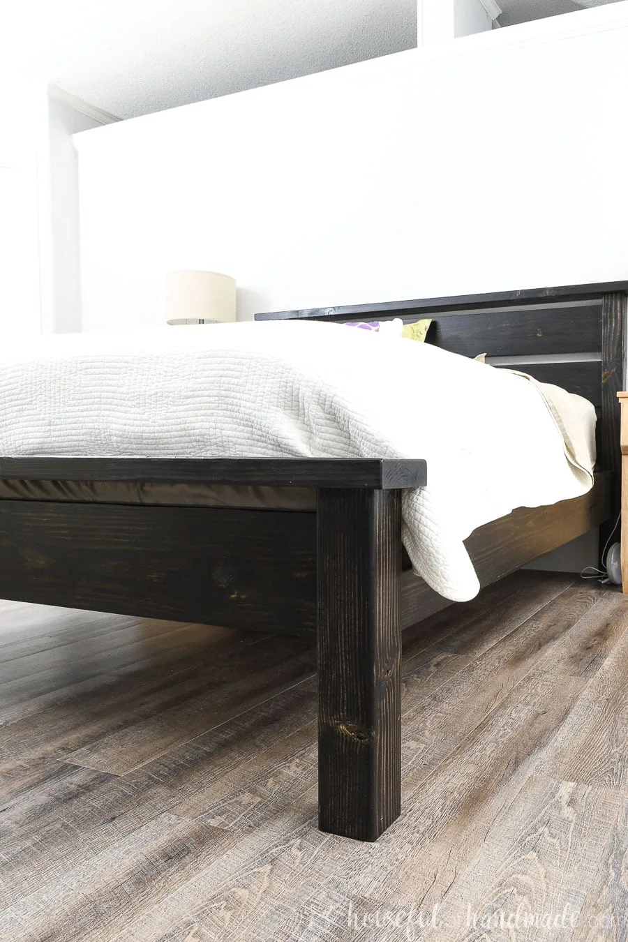 Side view of the black queen bed frame with headboard and footboard made from inexpensive lumber.