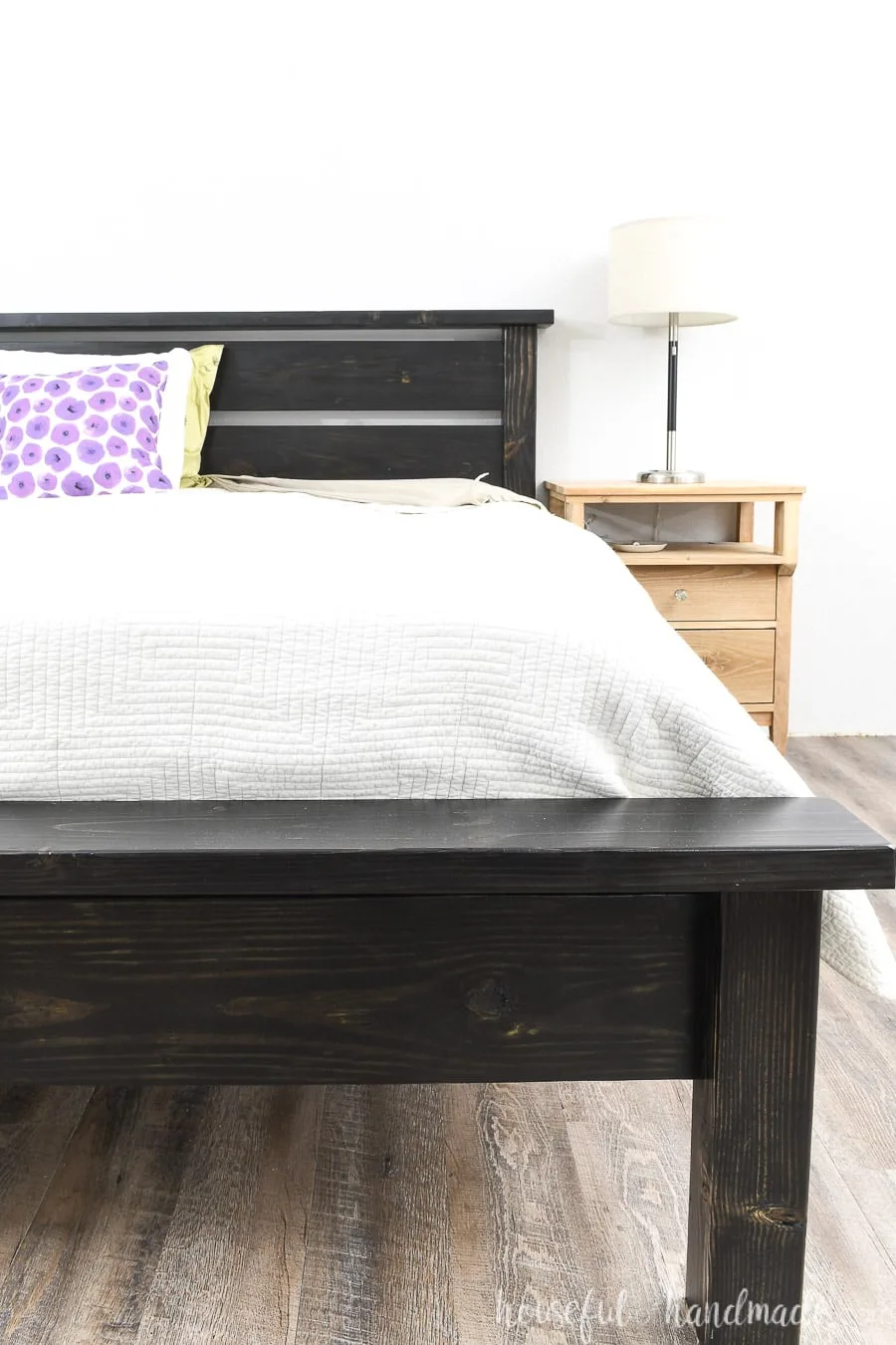 DIY platform bed that looks like a traditional bed with a slatted headboard sitting next to a nightstand.