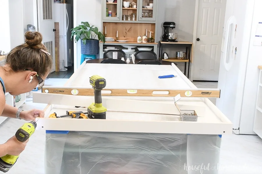 Attaching the melamine covered wood to the front of the kitchen island form. 